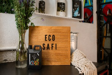 Grounded eco-friendly cleaning products displayed in a home beside an Eco Safi sign and indoor plants