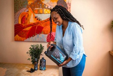 Woman using Grounded eco-friendly cleaning products at home beside a potted plant