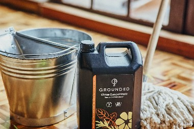 Grounded citrus cleaning concentrate beside a mop and bucket for a home cleaning reset